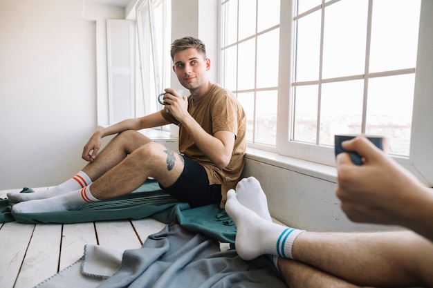 Giovane che guarda il suo amico mentre si tiene la tazza di caffè