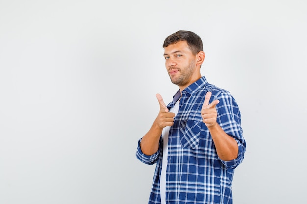 Giovane che indica con il gesto della pistola in camicia e che sembra fiducioso. vista frontale.