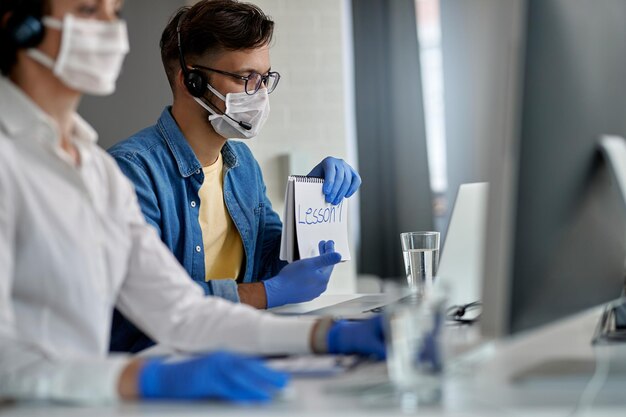 Giovane che indossa una maschera protettiva mentre tiene lezioni online al computer durante l'epidemia di coronavirus