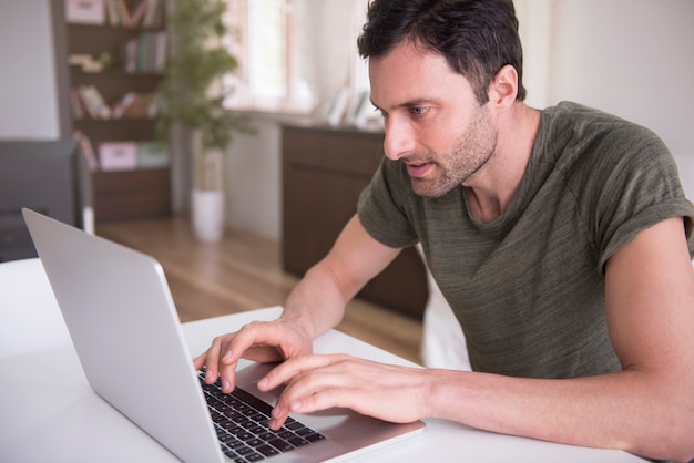 Giovane che lavora a casa con il suo laptop