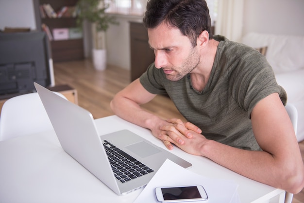 Giovane che lavora a casa con il suo laptop