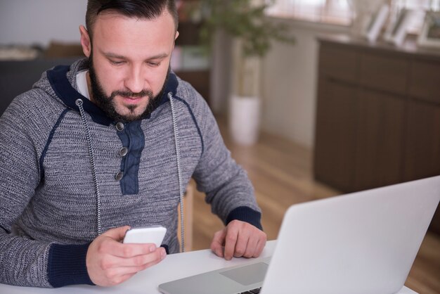 Giovane che lavora a casa con il suo laptop