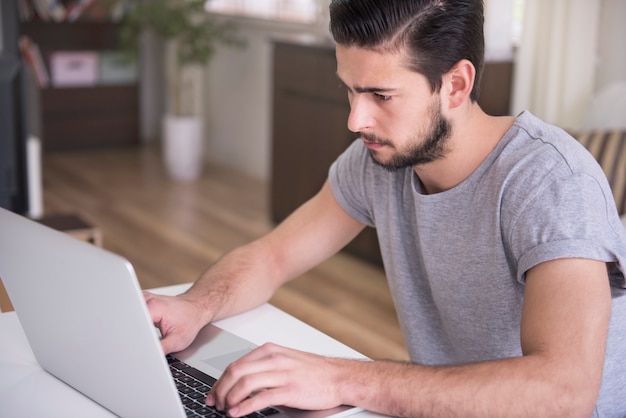 Giovane che lavora a casa con il suo laptop