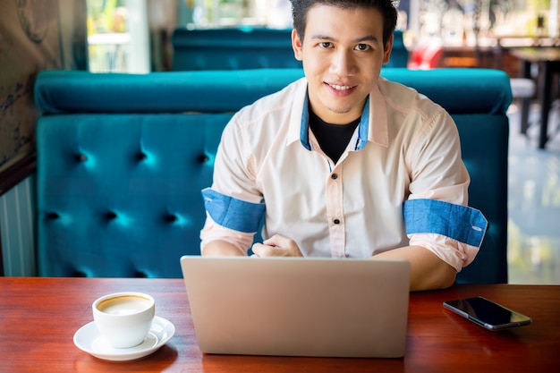 Giovane che lavora con il computer portatile in caffè