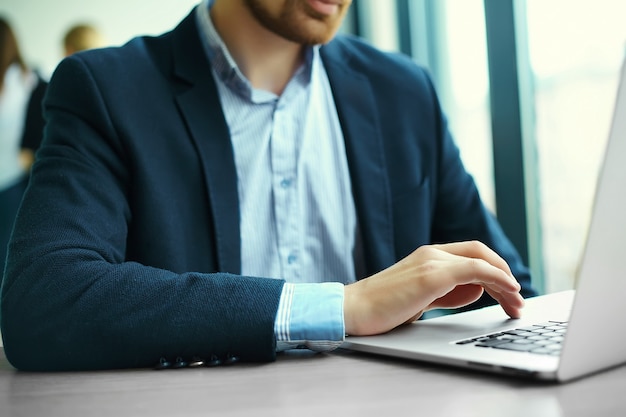 Giovane che lavora con il computer portatile, le mani dell'uomo sul computer portatile, uomo d'affari nel luogo di lavoro