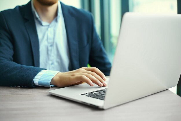 Giovane che lavora con il computer portatile, le mani dell'uomo sul computer portatile, uomo d'affari nel luogo di lavoro