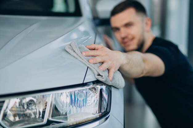 Giovane che lucida la sua automobile con lo straccio