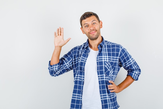 Giovane che mostra il palmo con la mano sulla vita in camicia e sembra allegro. vista frontale.