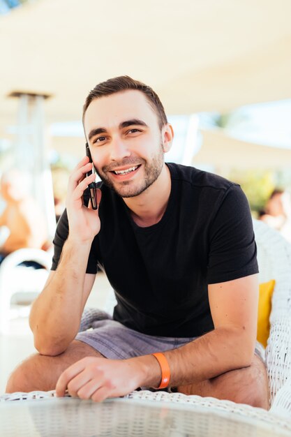 Giovane che parla uno smartphone sulla terrazza in riva al mare. .