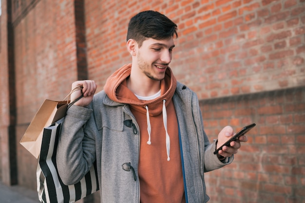 Giovane che per mezzo del suo telefono cellulare sulla via.