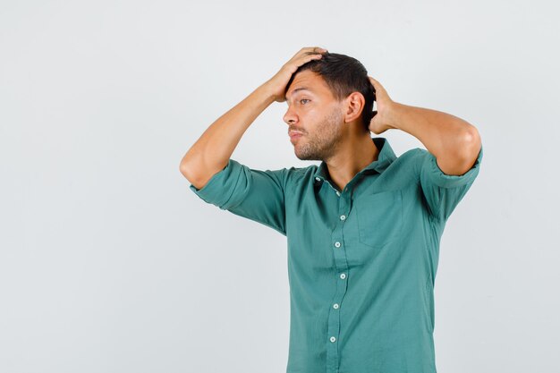 Giovane che propone con le mani sulla testa in camicia e alla moda