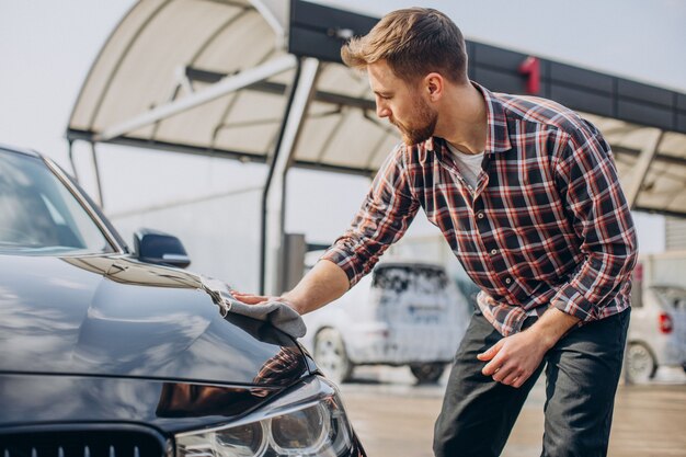 Giovane che pulisce la sua auto dopo l'autolavaggio