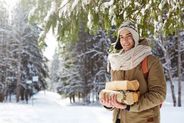 Giovane che raccoglie legno in foresta