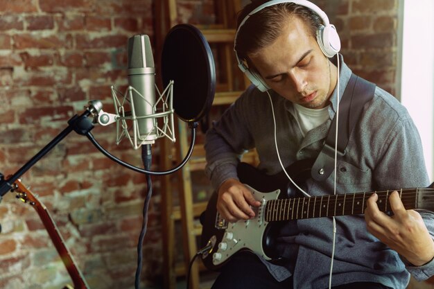 Giovane che registra musica, suona la chitarra e canta a casa