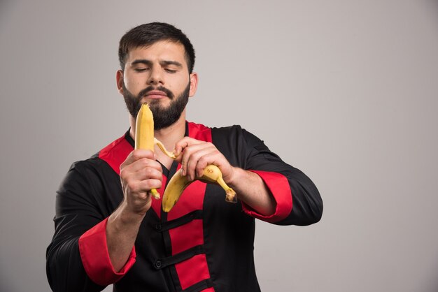 Giovane che sbuccia una banana sulla parete scura.