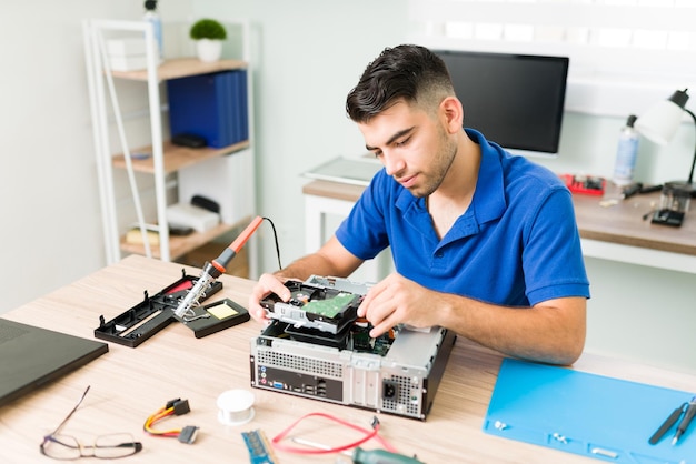 Giovane che scopre se la connessione funziona. Tecnico ispanico che collega un nuovo disco rigido su un computer e controlla l'hardware