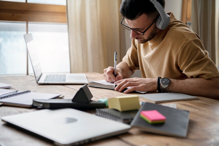 Foto gratuito giovane che scrive su un taccuino durante la sessione di studio