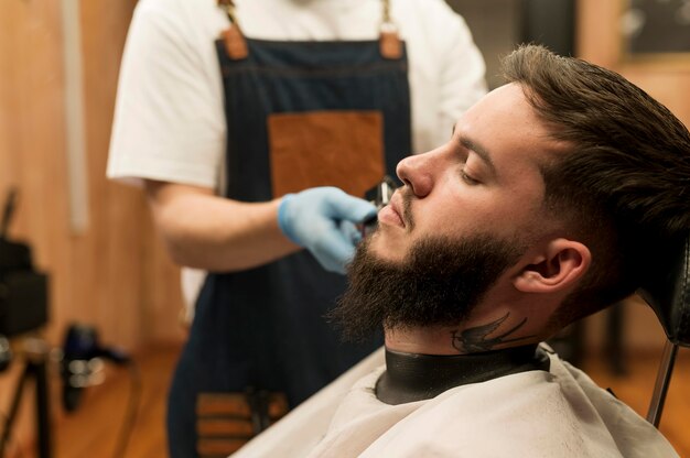 Giovane che si fa acconciare la barba dal barbiere