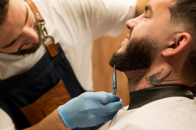 Giovane che si fa acconciare la barba dal barbiere