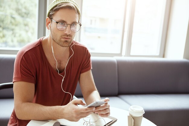 Giovane che si siede in caffè che ascolta la musica