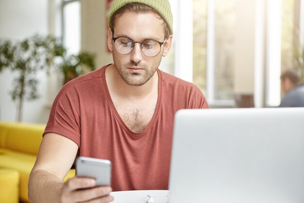 Giovane che si siede nella caffetteria con il computer portatile