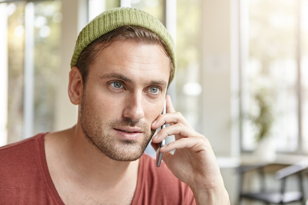 Giovane che si siede nella caffetteria parlando al telefono