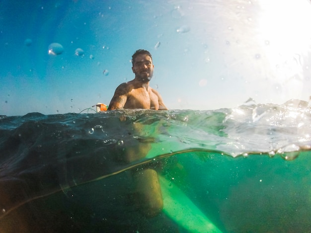 Giovane che si siede sulla tavola da surf in mare