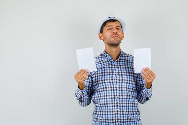 Giovane che tiene fogli di carta in camicia controllata