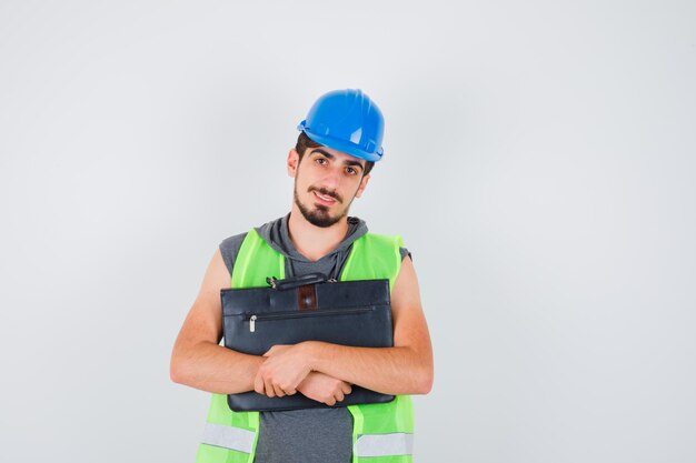 Giovane che tiene la cassetta degli attrezzi da costruzione in uniforme da costruzione e sembra felice