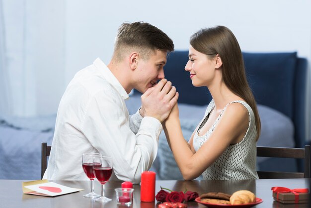 Giovane che tiene le mani della donna al tavolo