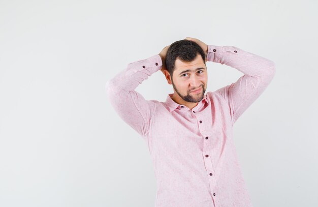 Giovane che tiene le mani dietro la testa in camicia rosa e che sembra bello