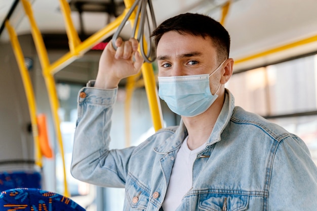 Giovane che viaggia in autobus urbano che indossa la mascherina chirurgica