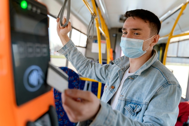 Giovane che viaggia in autobus urbano pagando con la carta dell'autobus