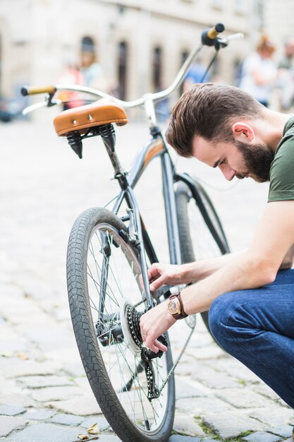 Giovane ciclista maschio che ripara la sua bicicletta