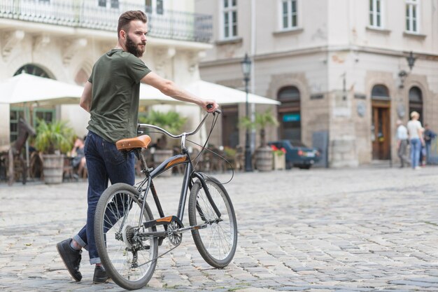 Giovane ciclista maschio con la sua bicicletta in strada