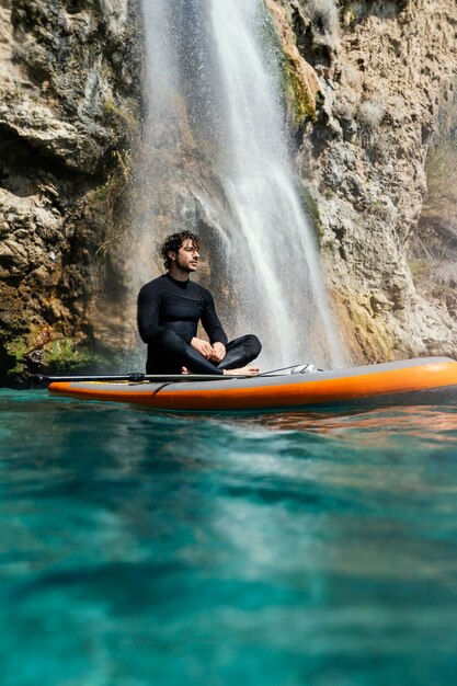 Giovane colpo completo che si siede sulla tavola da surf