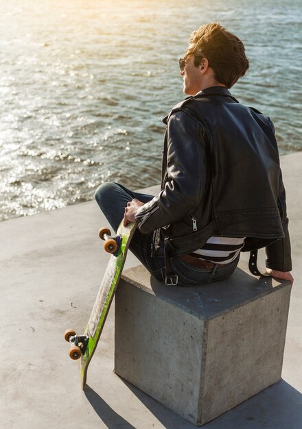 Giovane con uno skateboard vicino al mare