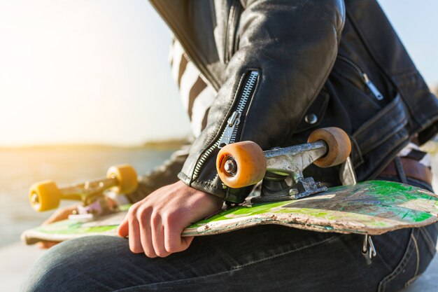 Giovane con uno skateboard vicino al mare