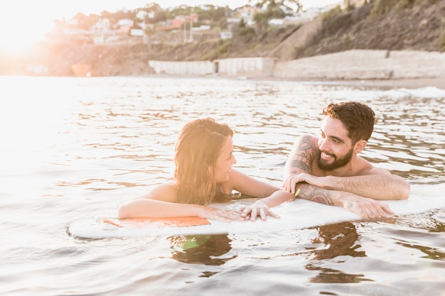 Giovane coppia che galleggia sulla tavola da surf