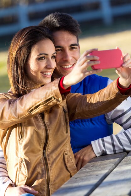 Giovane coppia che scatta foto con smartphone nel parco