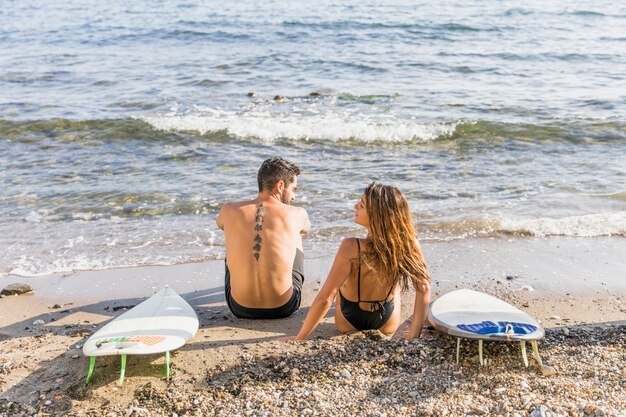 Giovane coppia con tavole da surf rilassante sulla spiaggia