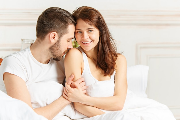 Giovane coppia eterosessuale adulta sdraiata sul letto in camera da letto