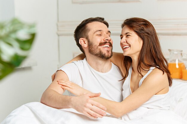 Giovane coppia eterosessuale adulta sdraiata sul letto in camera da letto