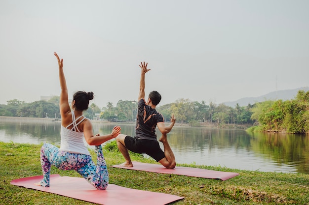 Giovane coppia facendo yoga accanto al lago