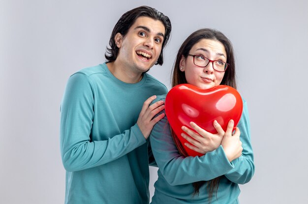 Giovane coppia il giorno di San Valentino ragazzo eccitato abbracciato ragazza con palloncino cuore isolato su sfondo bianco white