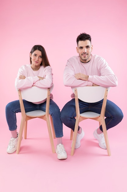 Giovane coppia in abiti simili sulle sedie