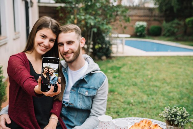 Giovane coppia in amore prendendo selfie in giardino