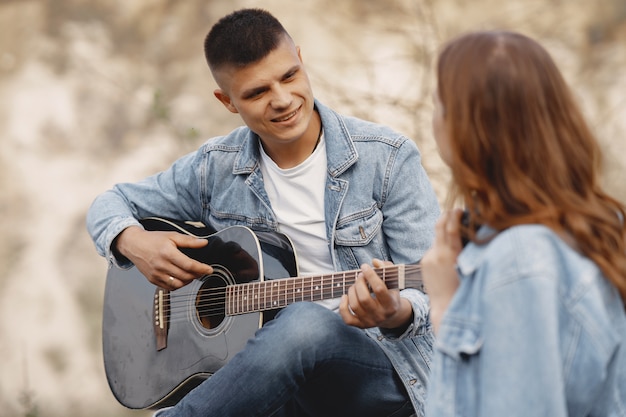 Giovane coppia innamorata, ragazzo a suonare la chitarra