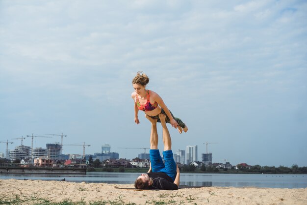 giovane coppia praticare yoga sullo sfondo della città