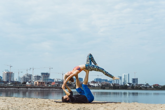giovane coppia praticare yoga sullo sfondo della città